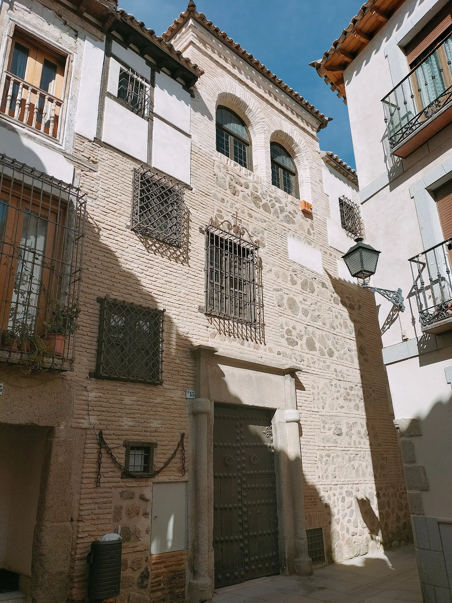 Fachada de ladrillo de la Casa de las Cadenas con portón claveteado y cadenas de hierro colgadas, en la calle Bulas de Toledo