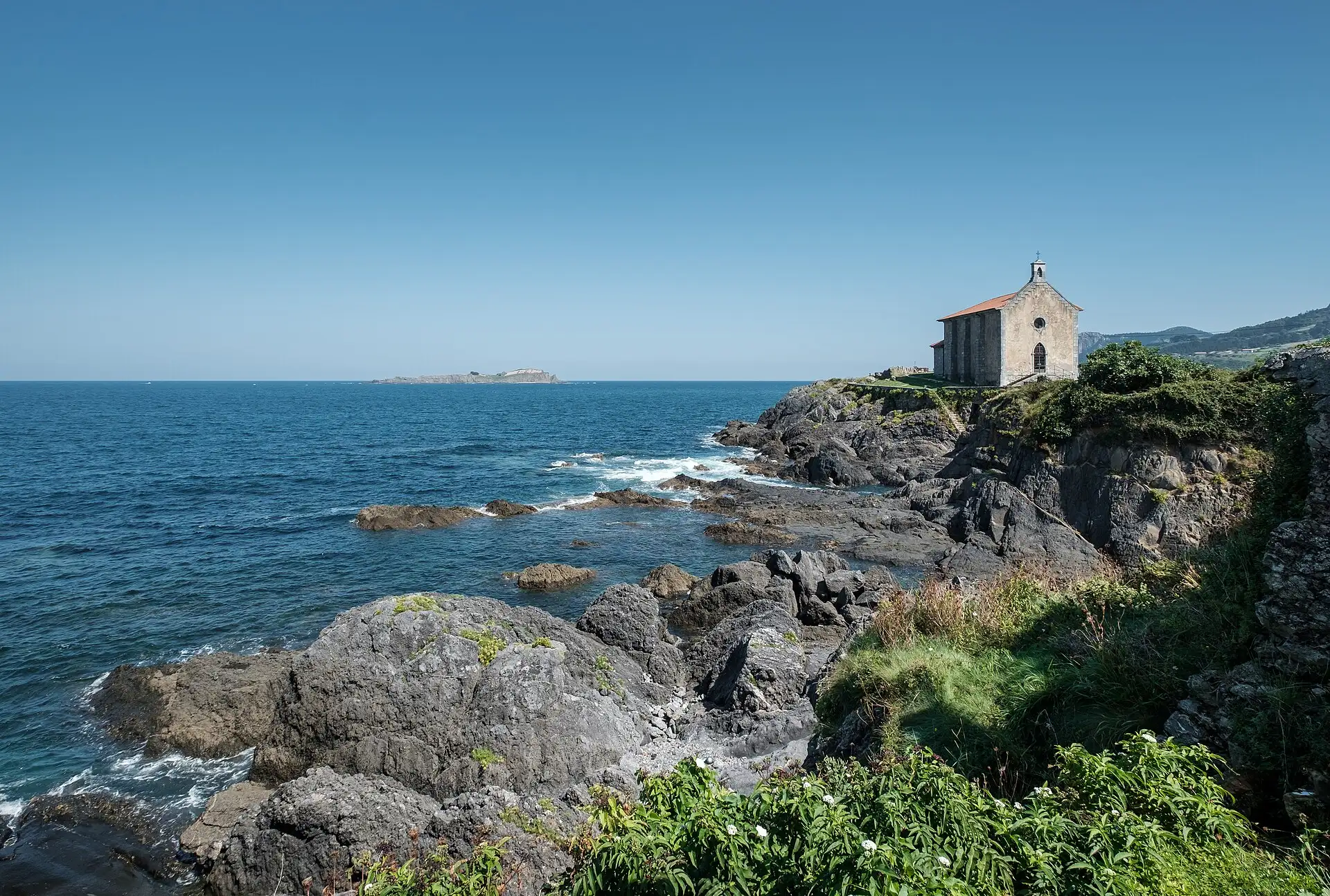 Ermita de Santa Catalina sobre las rocas de Mundaka, con el mar Cantábrico al fondo