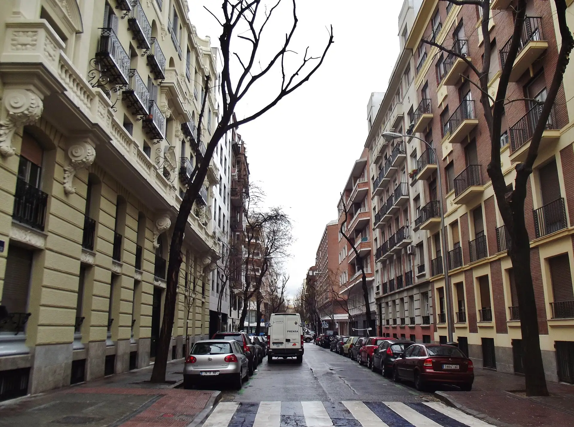 Calle de Nicasio Gallego en Madrid con edificios de balcones de hierro a ambos lados y árboles sin hojas