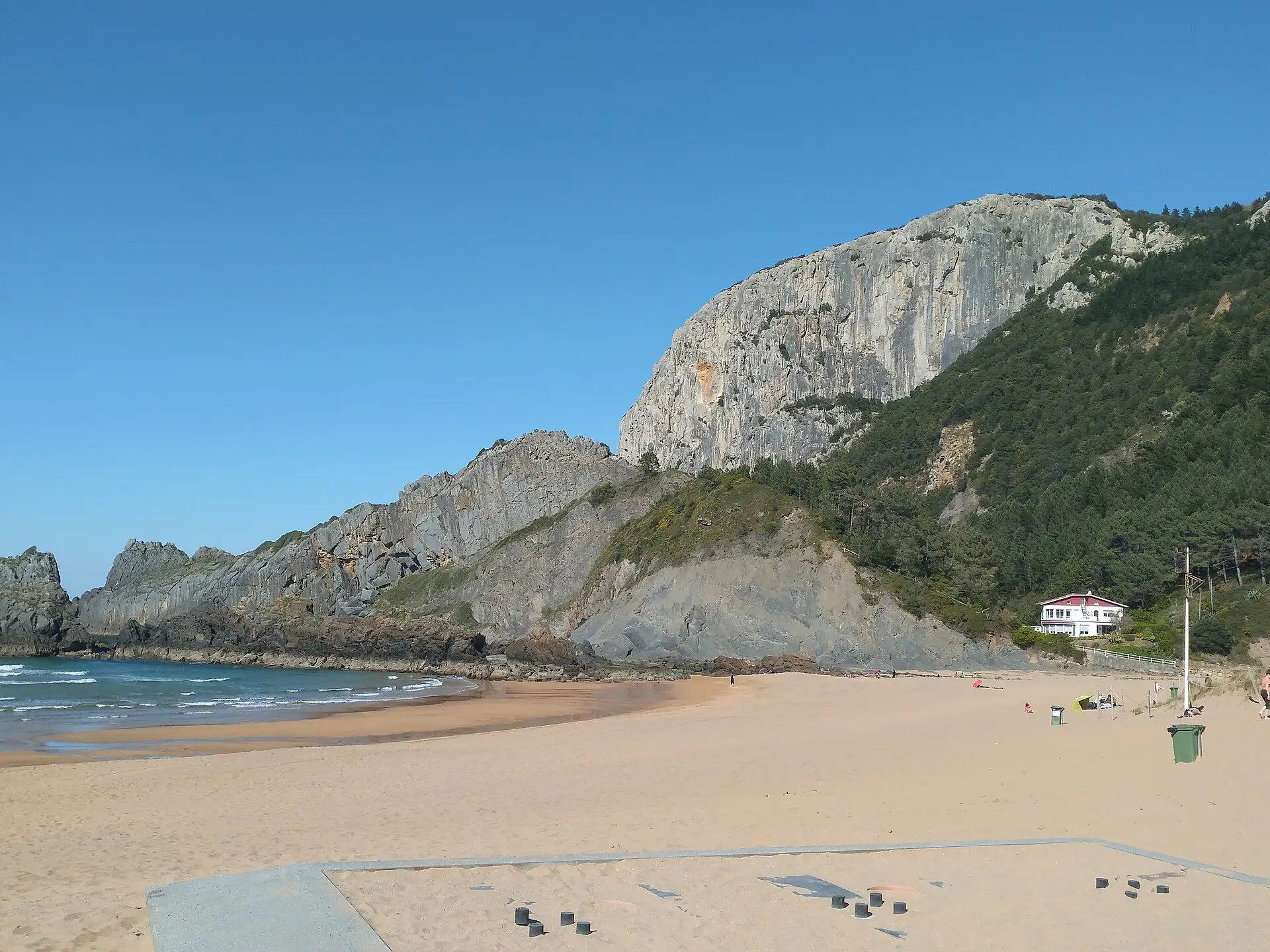 Arenal de la playa de Laga con la pared caliza del monte Ogoño y una casa al pie