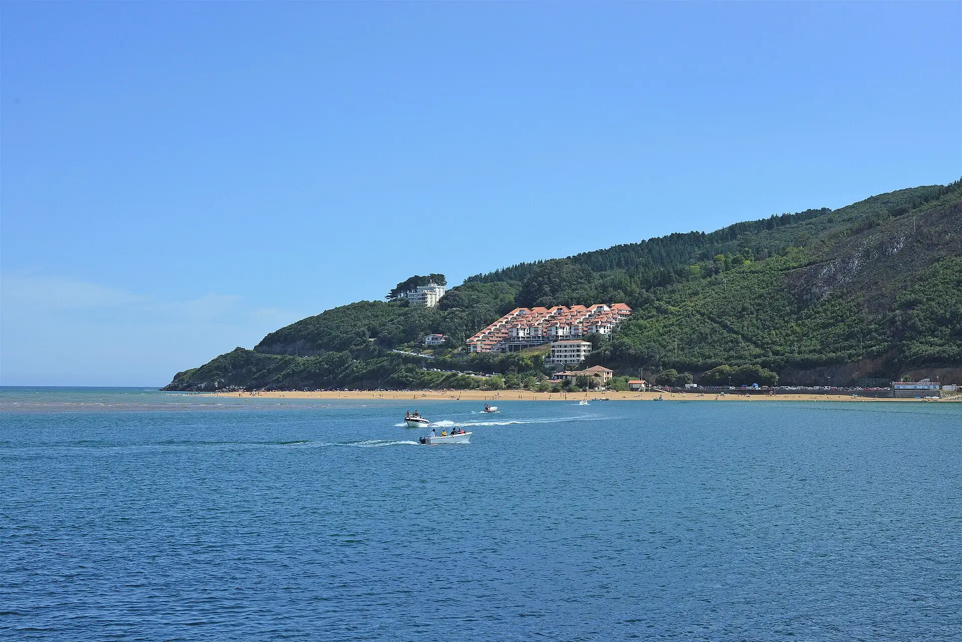 Playa de Laida vista desde Mundaka al otro lado de la ría, con lanchas en el agua
