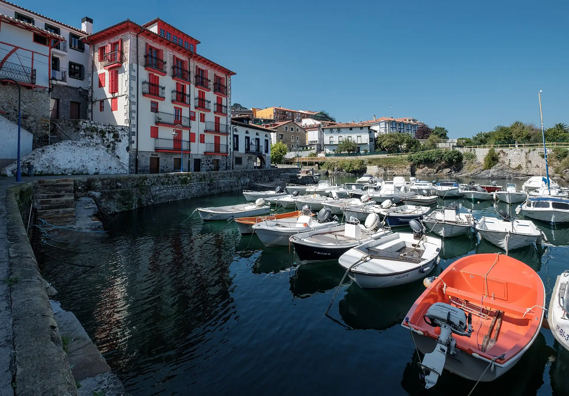 Barcas amarradas en el puerto de Mundaka frente a un edificio blanco y rojo